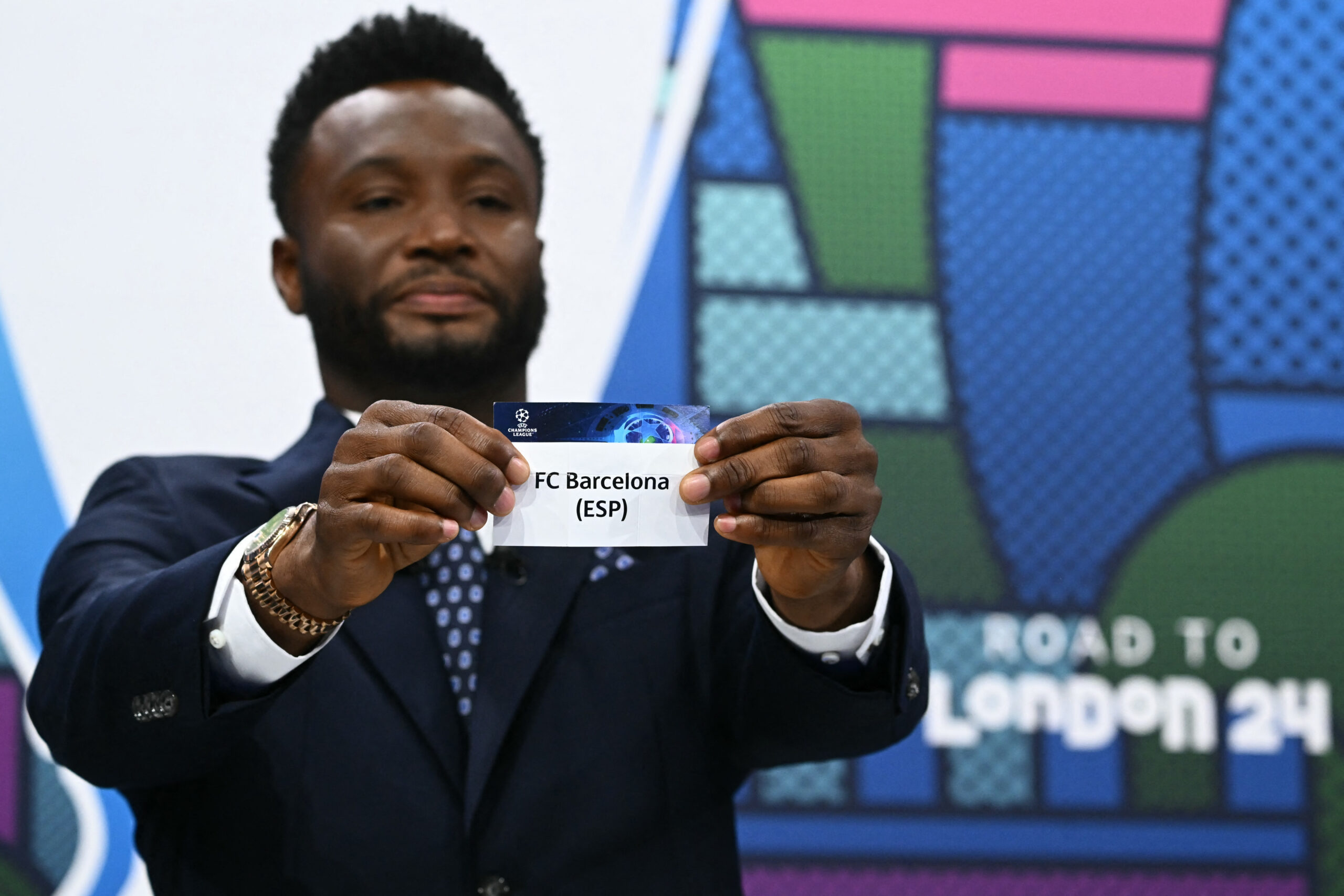 Former Nigerian footballer John Obi Mikel holds the paper slip of FC Barcelona during the 2023-2024 UEFA Champions League football tournament quarter-finals and semi-finals draw at the House of European Football in Nyon, on March 15, 2024.