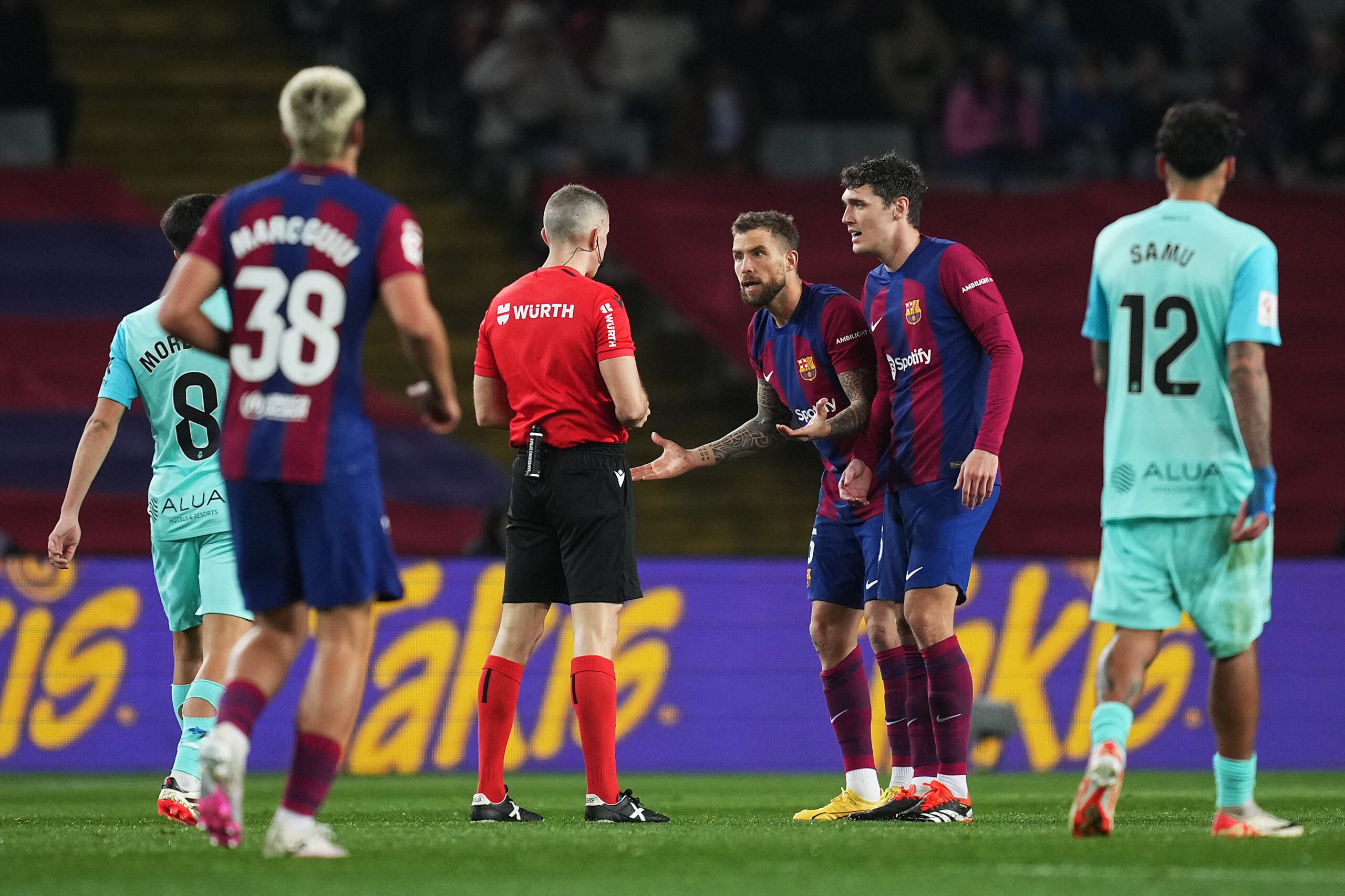 BARCELONA, SPAIN - MARCH 08: Inigo Martinez of FC Barcelona reacts after receiving a yellow card by referee Iglesias Villanueva during the LaLiga EA Sports match between FC Barcelona and RCD Mallorca at Estadi Olimpic Lluis Companys on March 08, 2024 in Barcelona, Spain.