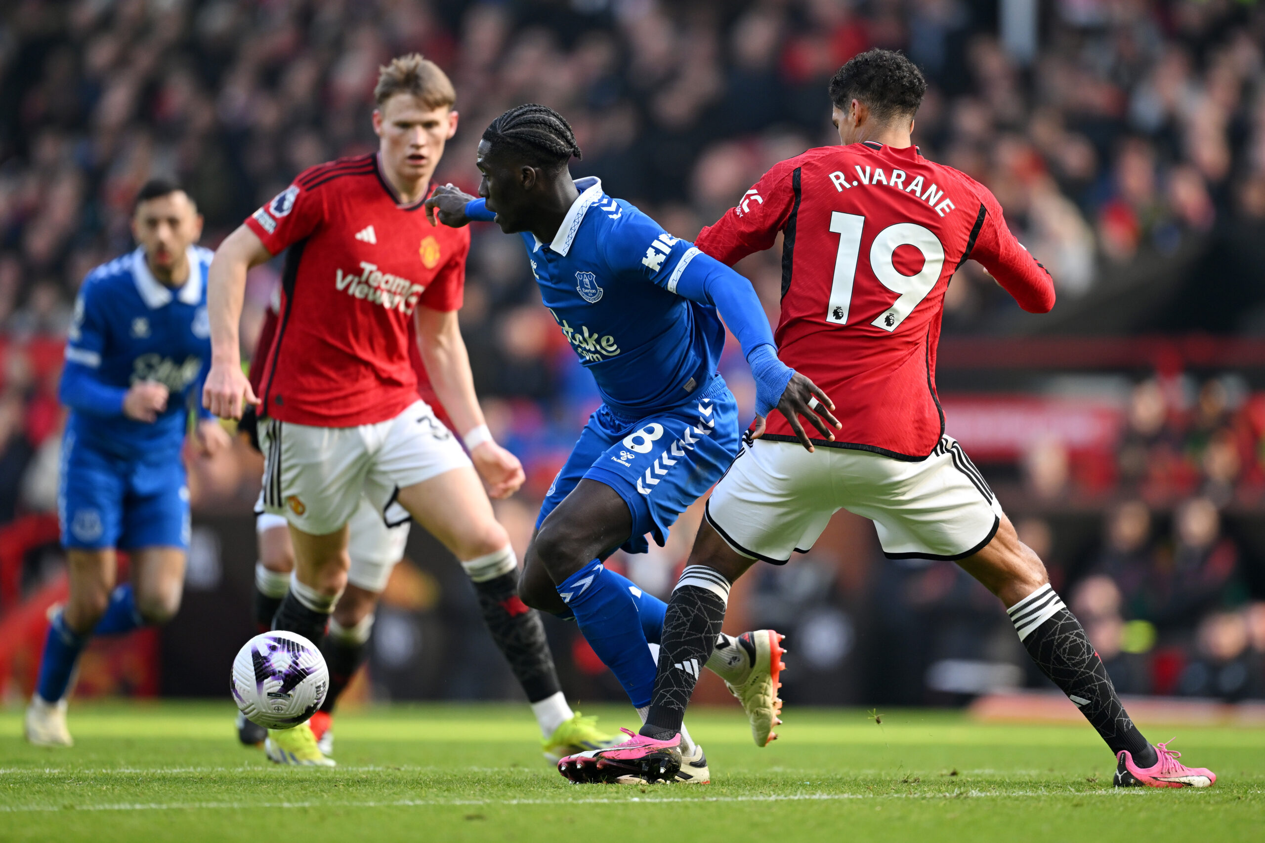 MANCHESTER, ENGLAND - MARCH 09: Amadou Onana of Everton is challenged by Raphael Varane of Manchester United during the Premier League match between Manchester United and Everton FC at Old Trafford on March 09, 2024 in Manchester, England.