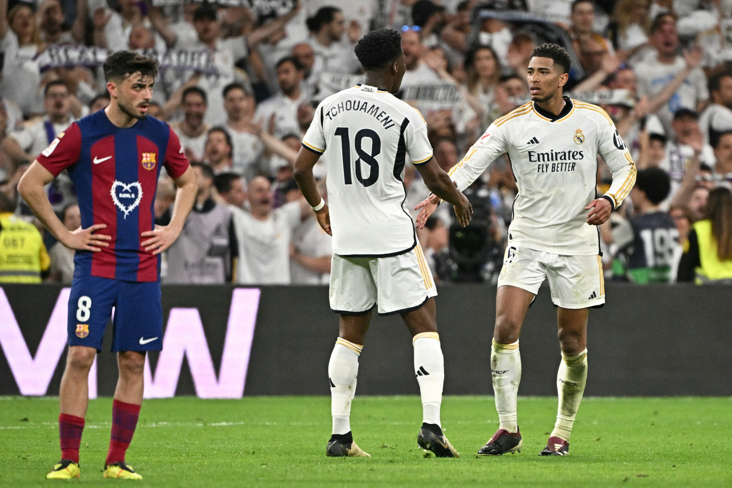 Real Madrid's English midfielder #5 Jude Bellingham celebrates scoring his team's third goal with Real Madrid's French defender #18 Aurelien Tchouameni during the Spanish league football match between Real Madrid CF and FC Barcelona at the Santiago Bernabeu stadium in Madrid on April 21, 2024.