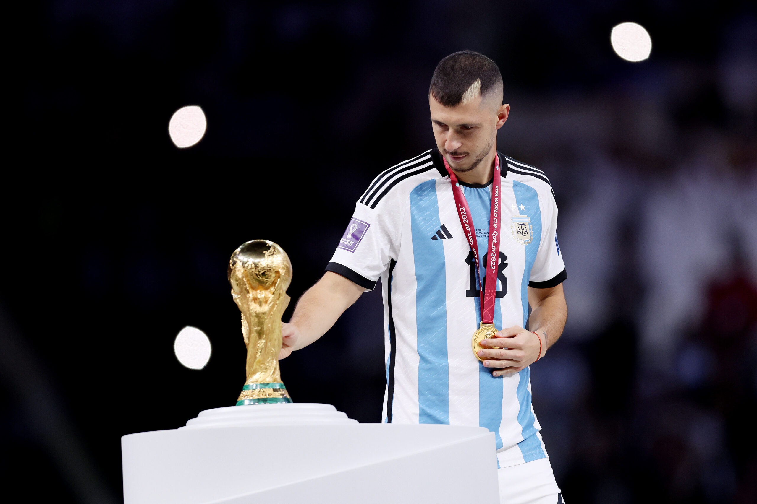 LUSAIL CITY, QATAR - DECEMBER 18: Guido Rodriguez of Argentina touches the FIFA World Cup Qatar 2022 Winner's Trophy as he walks past during the awards ceremony after the FIFA World Cup Qatar 2022 Final match between Argentina and France at Lusail Stadium on December 18, 2022 in Lusail City, Qatar.