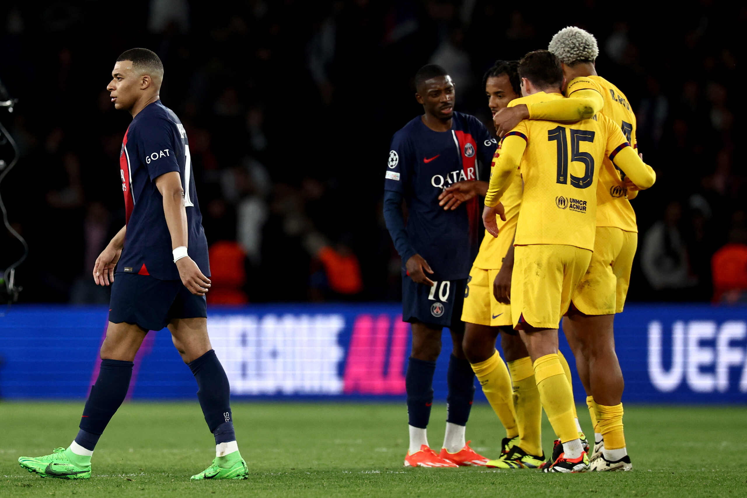 Paris Saint-Germain's French forward #07 Kylian Mbappe (L) walks off the field as Barcelona's players celebrate their victory at the end of the UEFA Champions League quarter final first leg football match between Paris Saint-Germain (PSG) and FC Barcelona at the Parc des Princes stadium in Paris on April 10, 2024.