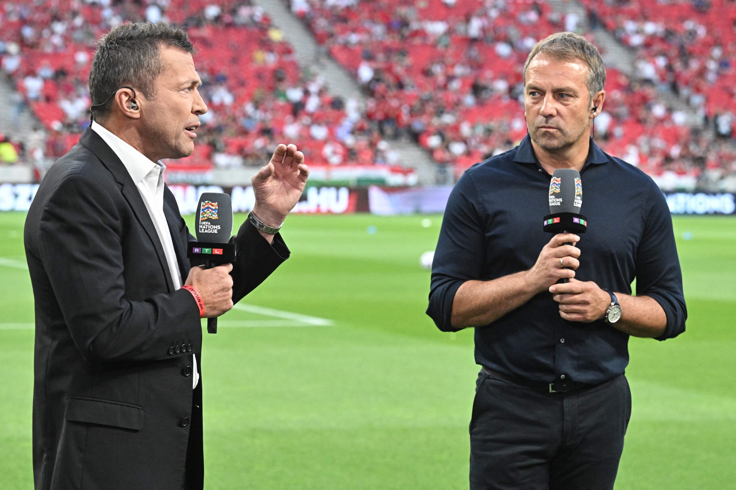 Germany's coach Hans-Dieter Flick (R) speaks with former Germany player Lothar Matthaus  for television prior to the UEFA Nations League football match Hungary v Germany in Budapest on June 11, 2022.