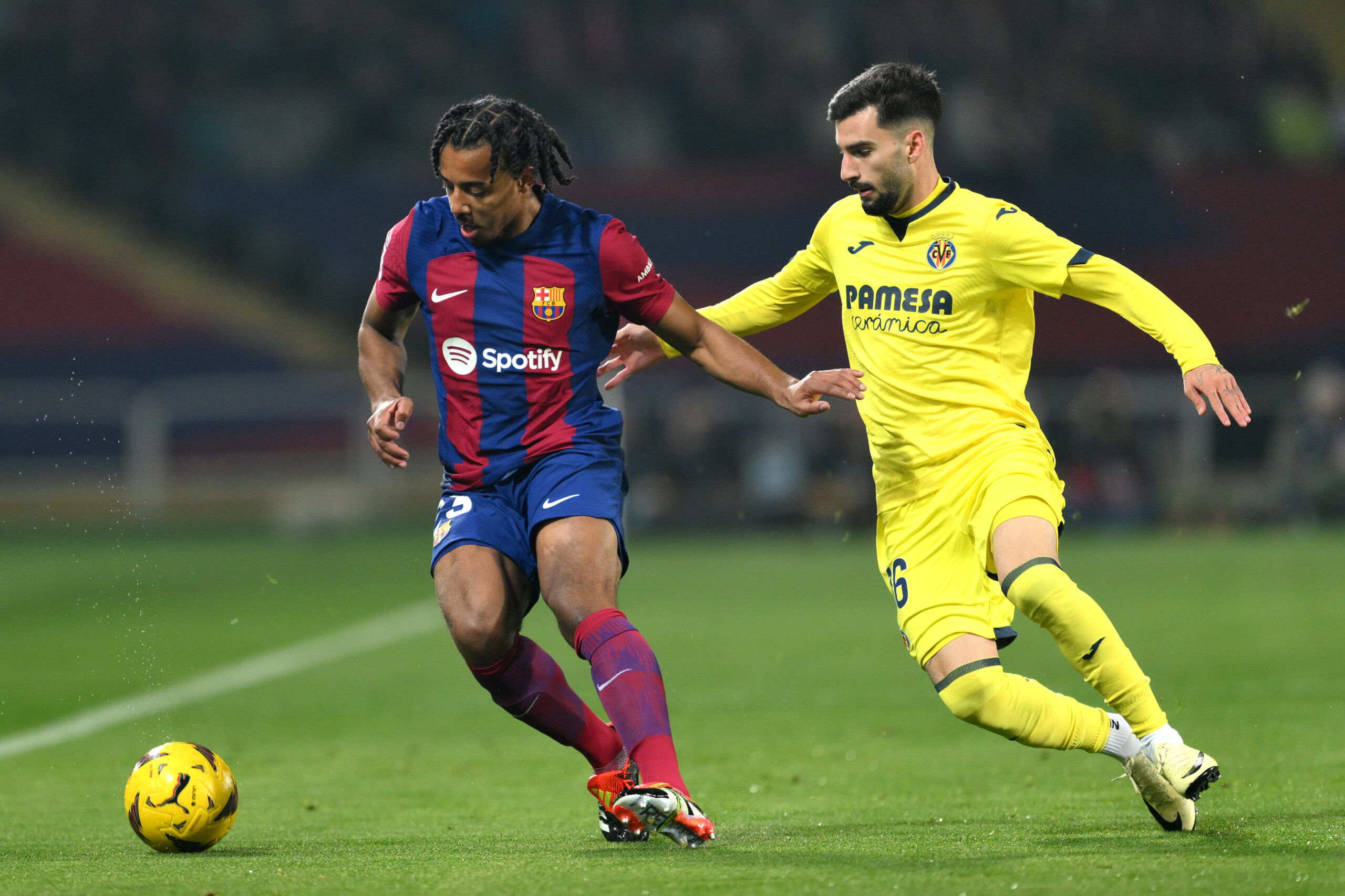 BARCELONA, SPAIN - JANUARY 27: Jules Kounde of FC Barcelona on the ball whilst under pressure from Alex Baena of Villarreal CF during the LaLiga EA Sports match between FC Barcelona and Villarreal CF at Estadi Olimpic Lluis Companys on January 27, 2024 in Barcelona, Spain.