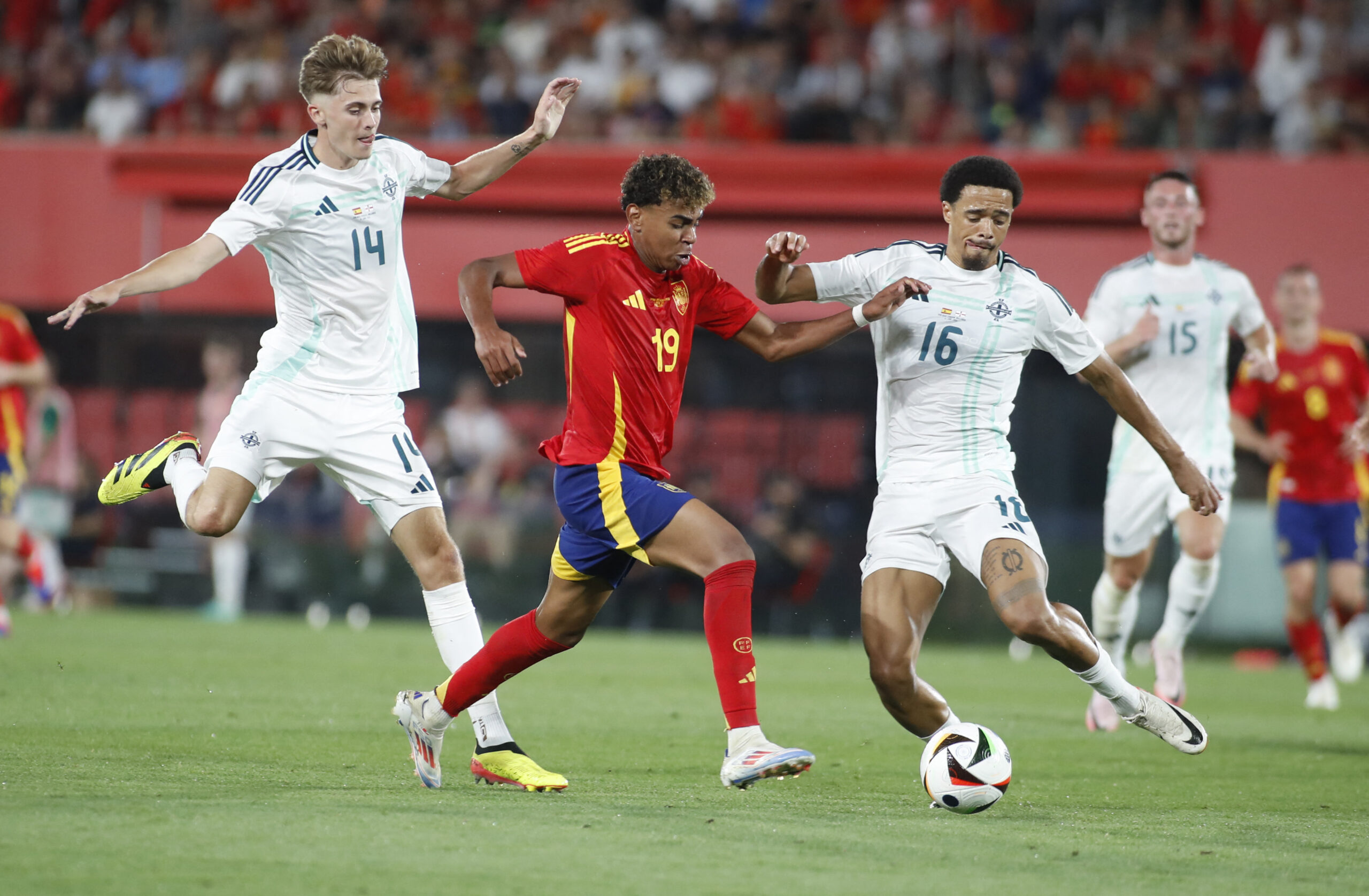 Spain's forward #19 Lamine Yamal fights for the ball with Northern Ireland's midfielder #14 Isaac Price and Northern Ireland's defender #16 Jamal Lewis during the international friendly football match between Spain and North Ireland at Son Moix stadium in Palma de Mallorca on June 8, 2024.