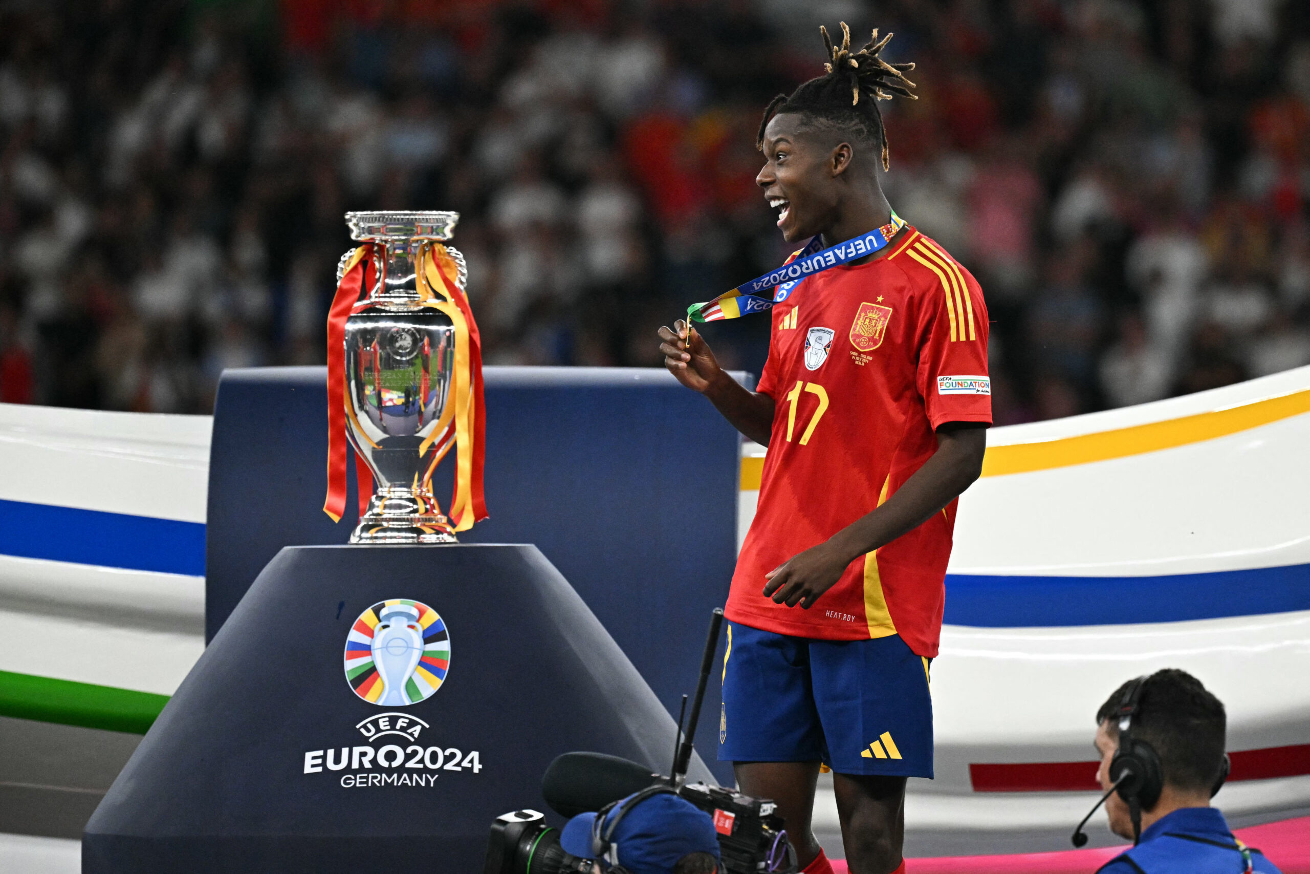 Spain's midfielder #17 Nico Williams celebrates with his gold medal next to the trophy after winning the UEFA Euro 2024 final football match between Spain and England at the Olympiastadion in Berlin on July 14, 2024.