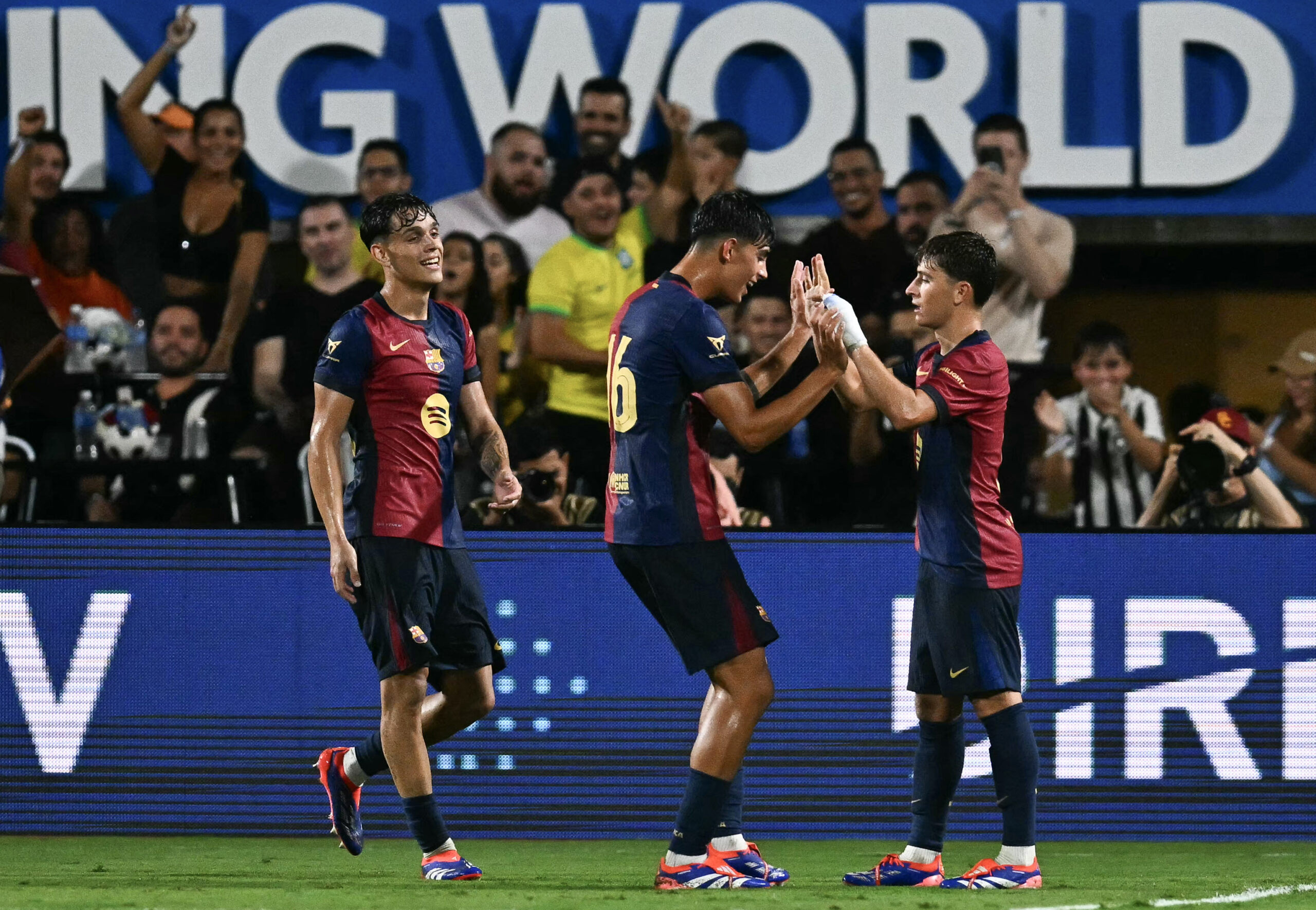 Barcelona's midfielder #6 Pablo Torre (R) celebrates with teammate #16 Marc Bernal (C) after Torre scored a goal during the 2024 FC Series pre-season friendly football match between FC Barcelona and Manchester City at Camping World Stadium in Orlando, Florida, on July 30, 2024.