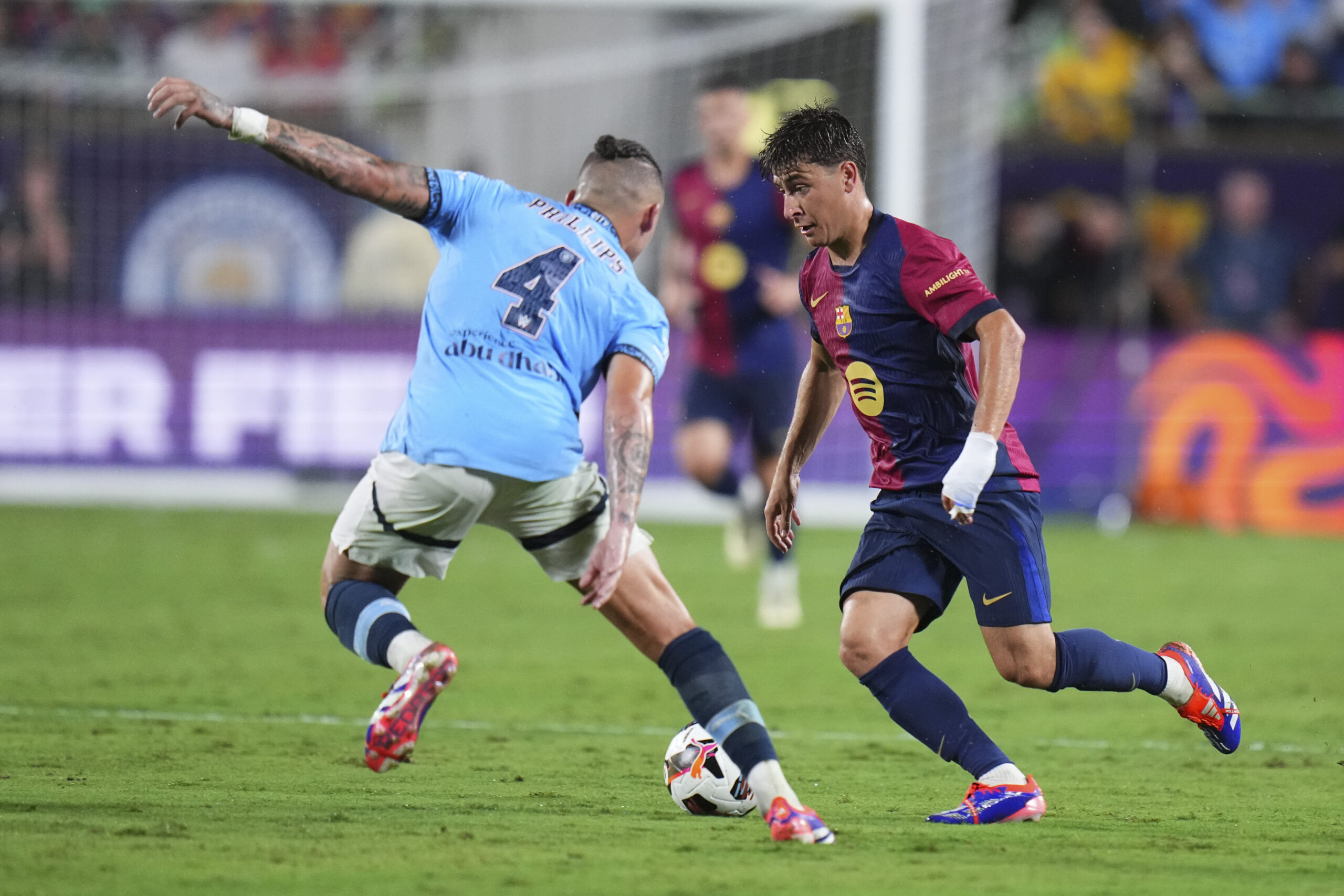 ORLANDO, FLORIDA - JULY 30: Pablo Torre #6 of FC Barcelona dribbles the ball against Kalvin Phillips #4 of Manchester City in the first half during a pre-season match between Manchester City and FC Barcelona at Camping World Stadium on July 30, 2024 in Orlando, Florida.